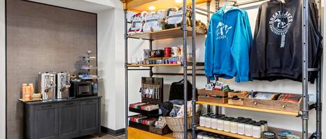 Una cafetería con una máquina de café, una tetera y una estantería con frascos de condimentos.