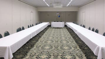 A conference room with two long tables, chairs, and a carpeted floor.