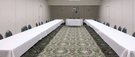 A conference room with two long tables, chairs, and a carpeted floor.
