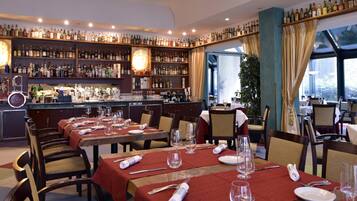 Un restaurant avec de nombreuses tables dressées pour le service, un bar bien garni de diverses bouteilles et une vue dégagée grâce à de grandes fenêtres.