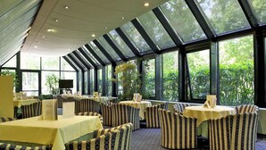 A restaurant with tables and chairs, large windows, and a ceiling with skylights. - Mercure Astoria Reggio Emilia (Reggio nell'Emilia)