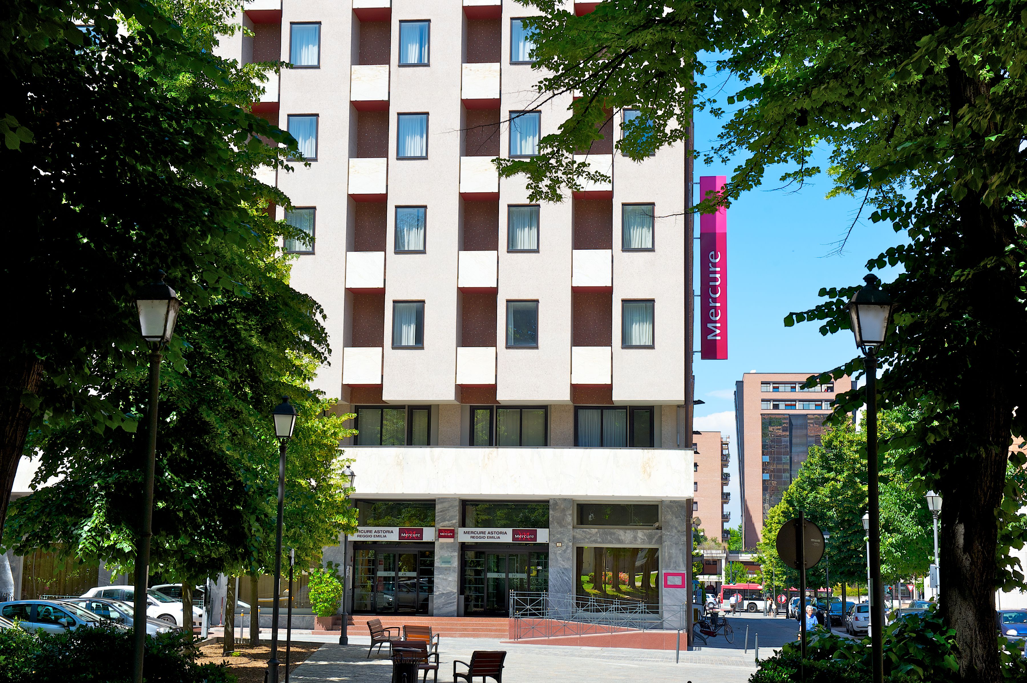 A multi-story hotel with a modern facade, large windows, and a prominent red sign.