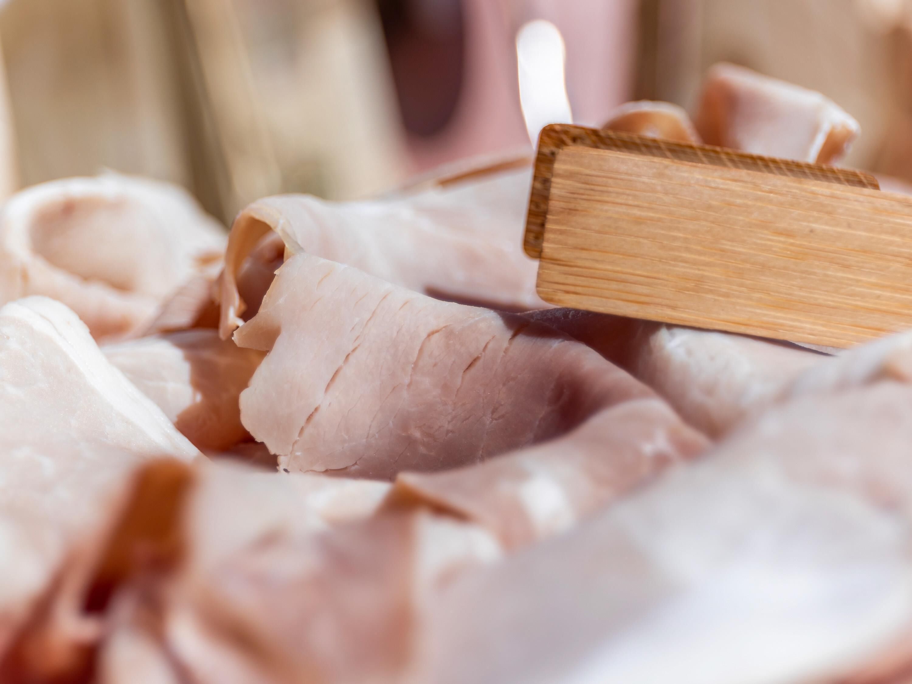 Un primo piano di fette di carne su un tagliere di legno.