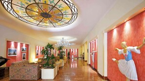 A hotel lobby with a marble floor, a chandelier, a large decorative ceiling, and a statue of a ballerina. - Mercure Astoria Reggio Emilia (Reggio nell'Emilia)