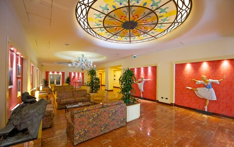A lobby with a chandelier, seating area, and a ballet dancer mural.