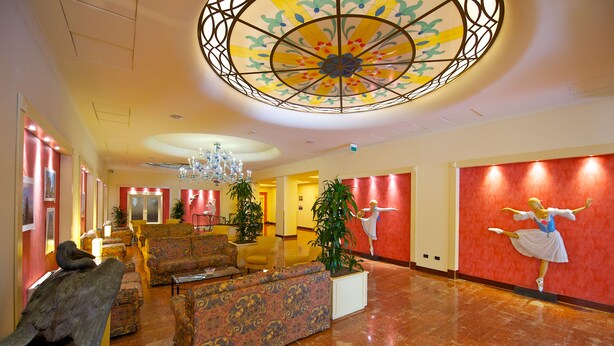 A lobby with a chandelier, seating area, and a ballet dancer mural. - Mercure Astoria Reggio Emilia (Reggio nell'Emilia)