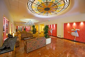 A lobby with a chandelier, seating area, and a ballet dancer mural. - Mercure Astoria Reggio Emilia (Reggio nell'Emilia)