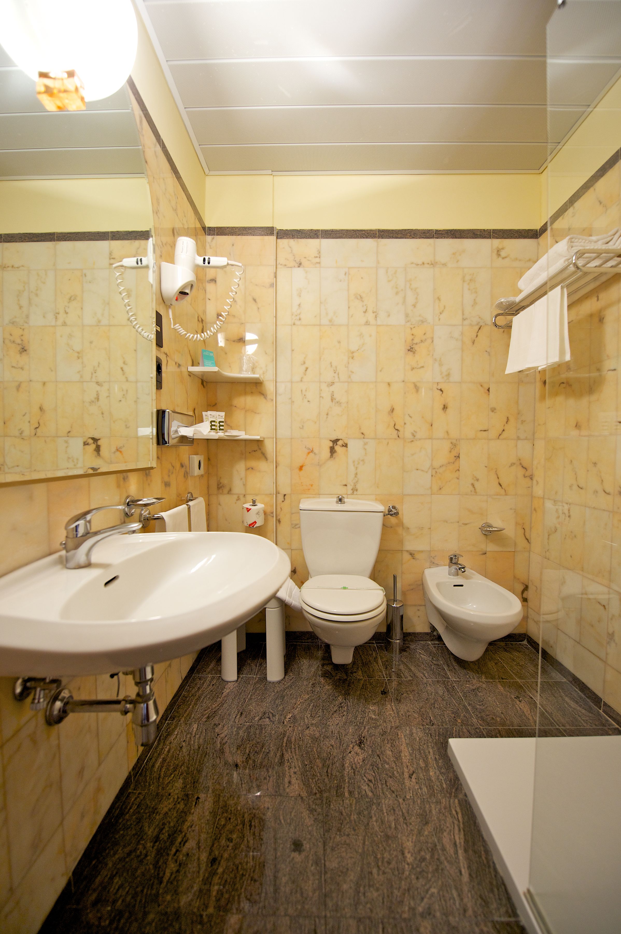 A bathroom with a sink, toilet, bidet, and a mirror.