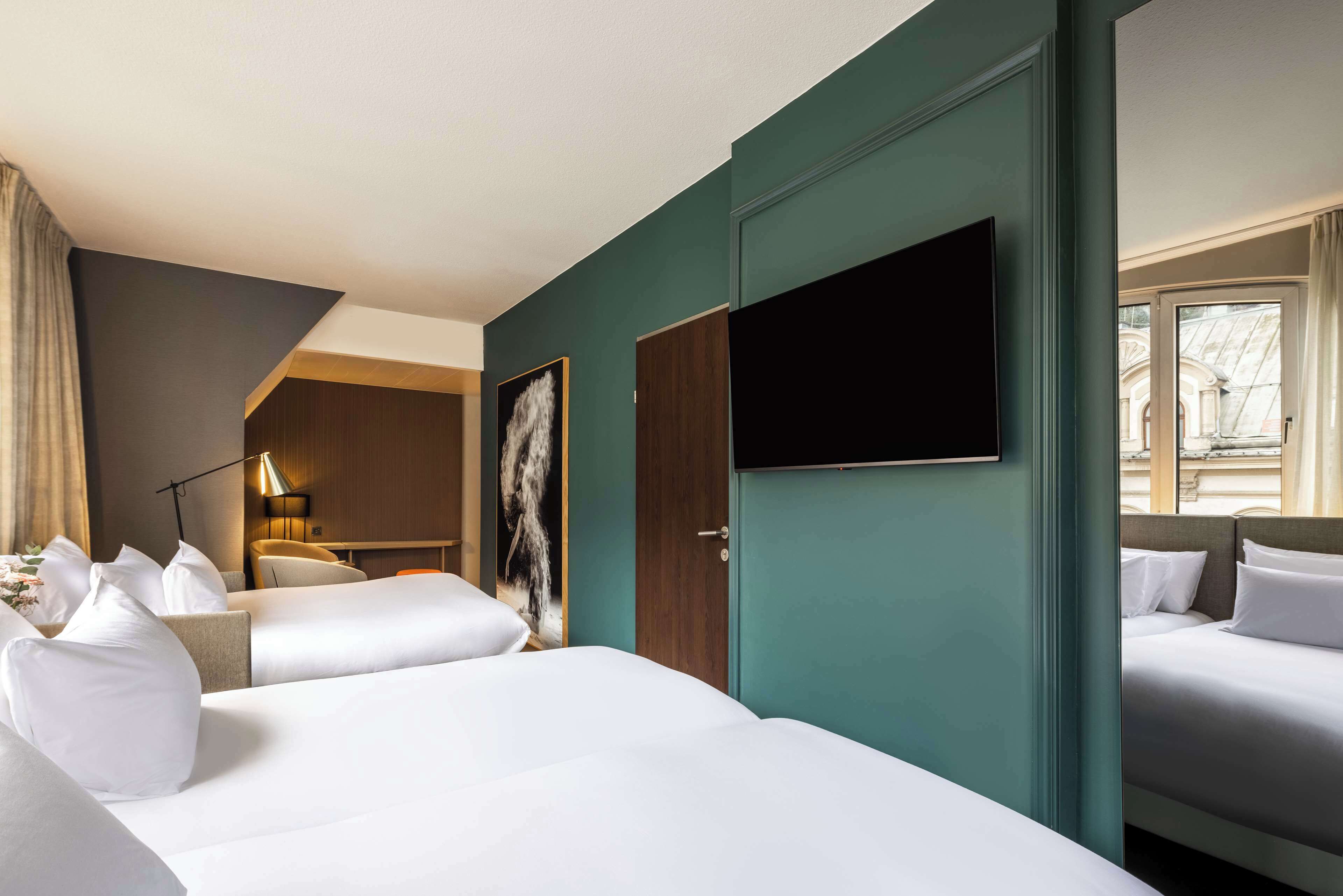 A hotel room with two beds, a flat-screen TV, a desk, and a chair.