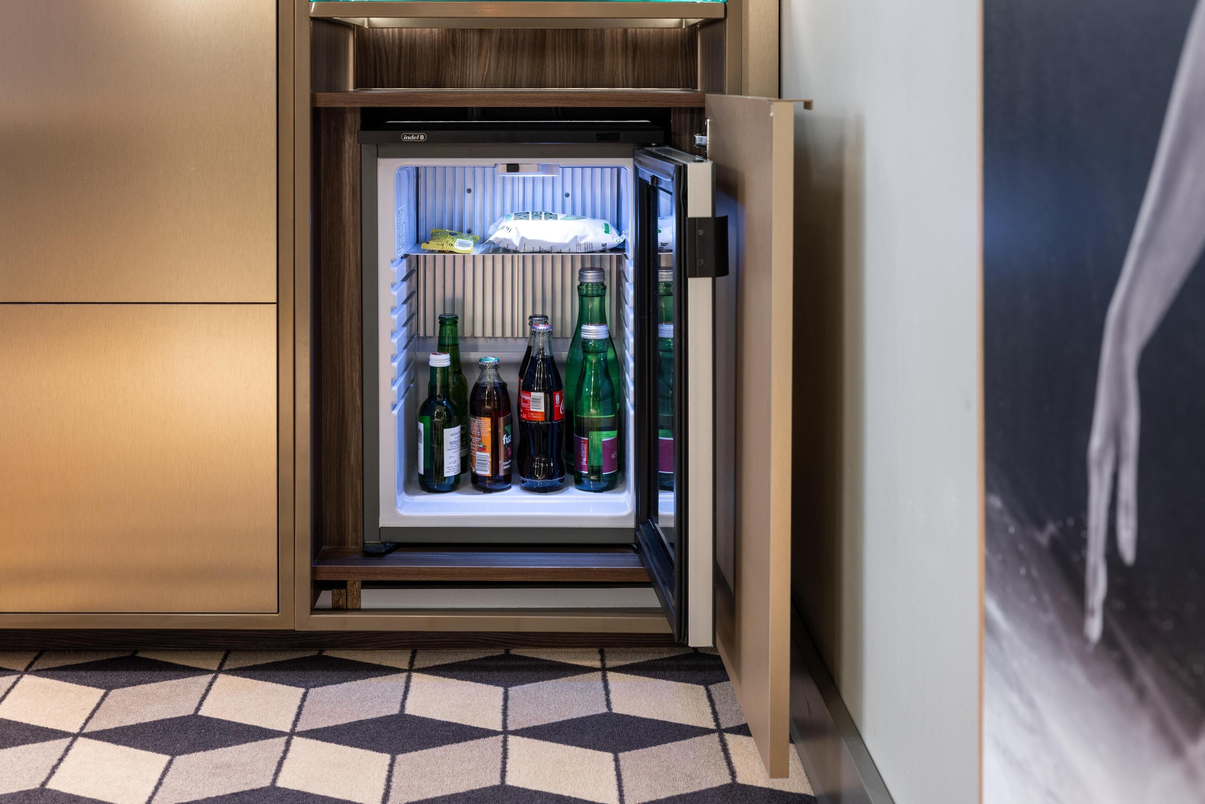 A compact refrigerator with a wooden finish, containing several bottles of beverages.