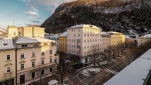 A multi-story building with a central courtyard, surrounded by snow-covered streets and a mountainous backdrop.