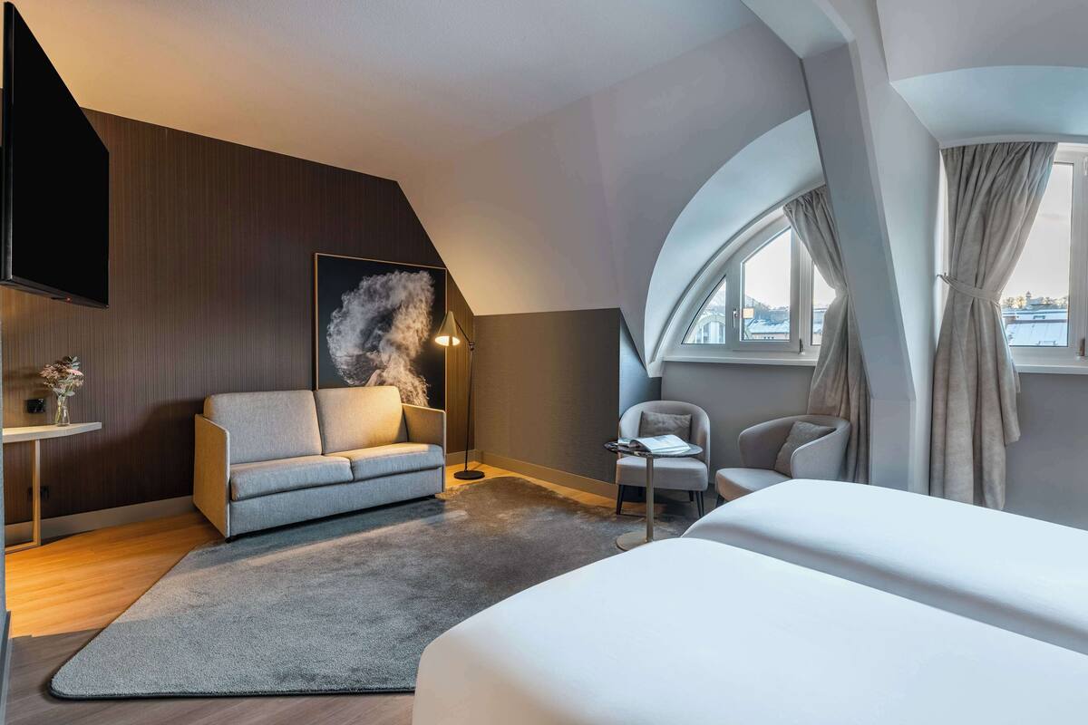 Une chambre d’hôtel moderne avec un canapé, un fauteuil et un lit.