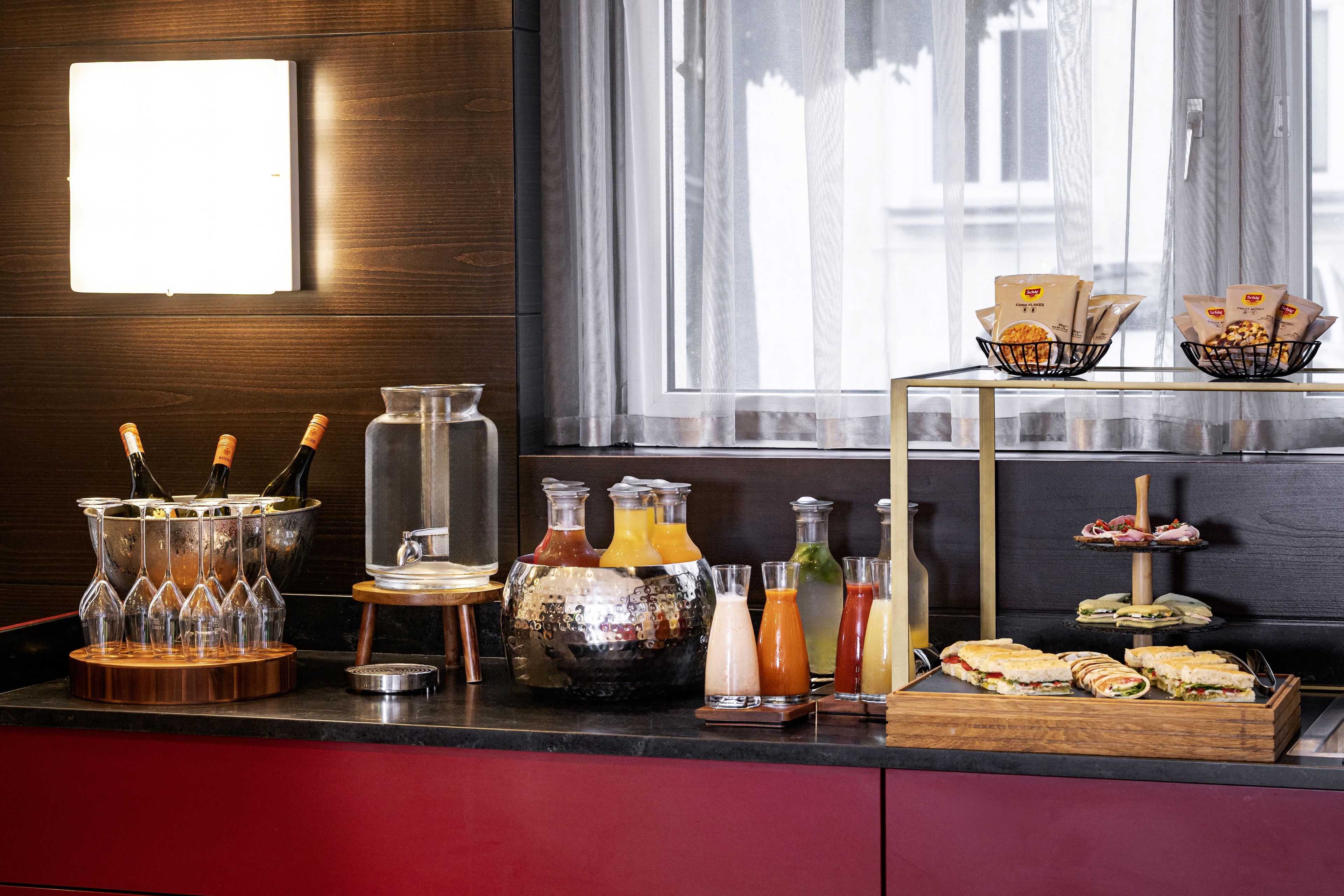 Un espace bar proposant une variété de boissons et d’en-cas, notamment des bouteilles, des verres et une assiette de sandwichs.