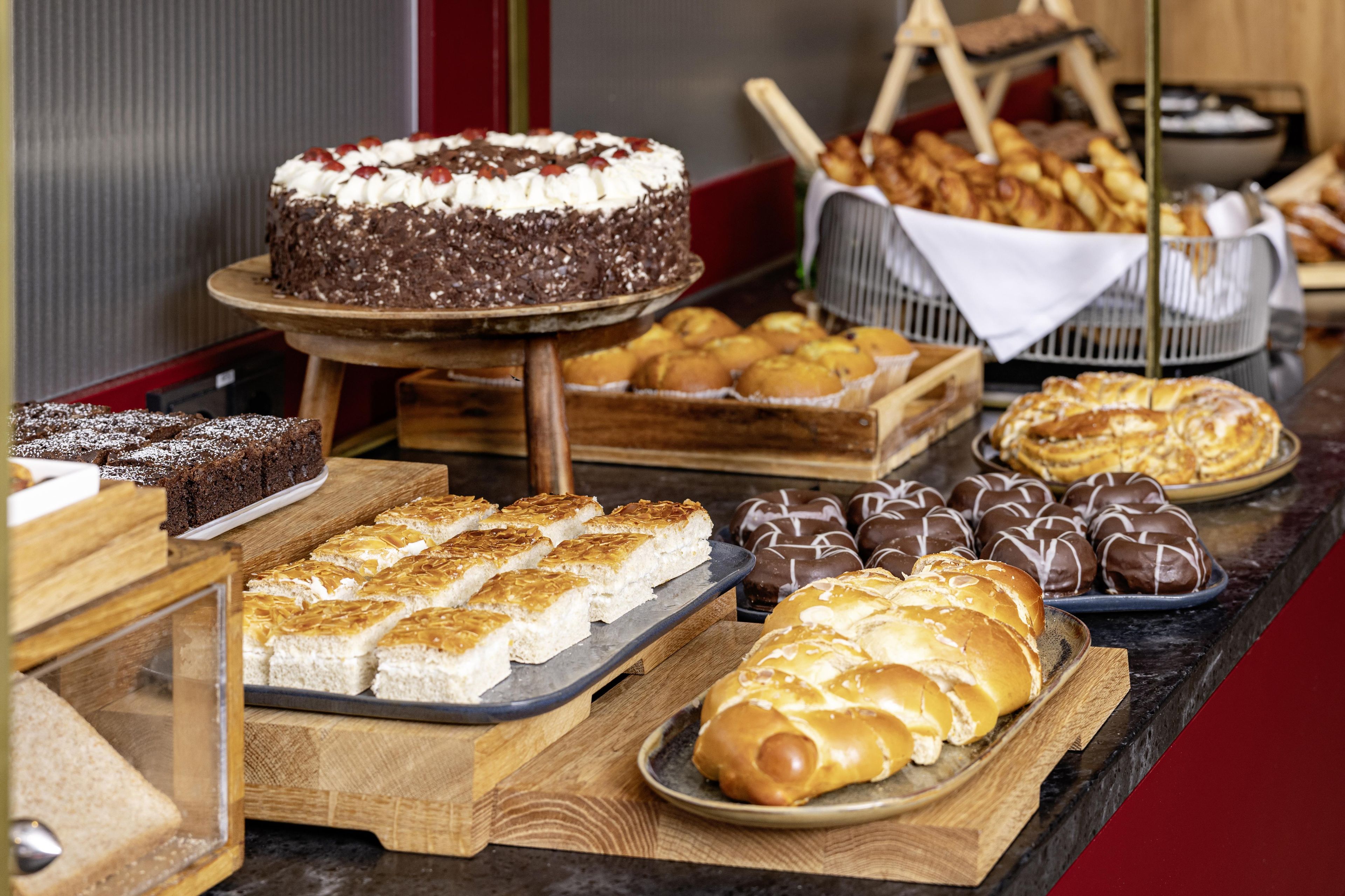 A variety of baked goods including cakes, pastries, and bread displayed on a counter.