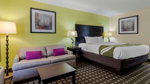 A hotel room with a bed, a sofa, two side tables with lamps, and two framed pictures on the walls. - Quality Inn Acworth North (Acworth)