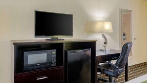 A hotel room with a desk, a television, a microwave, a refrigerator, a chair, and a lamp. - Quality Inn Acworth North (Acworth)