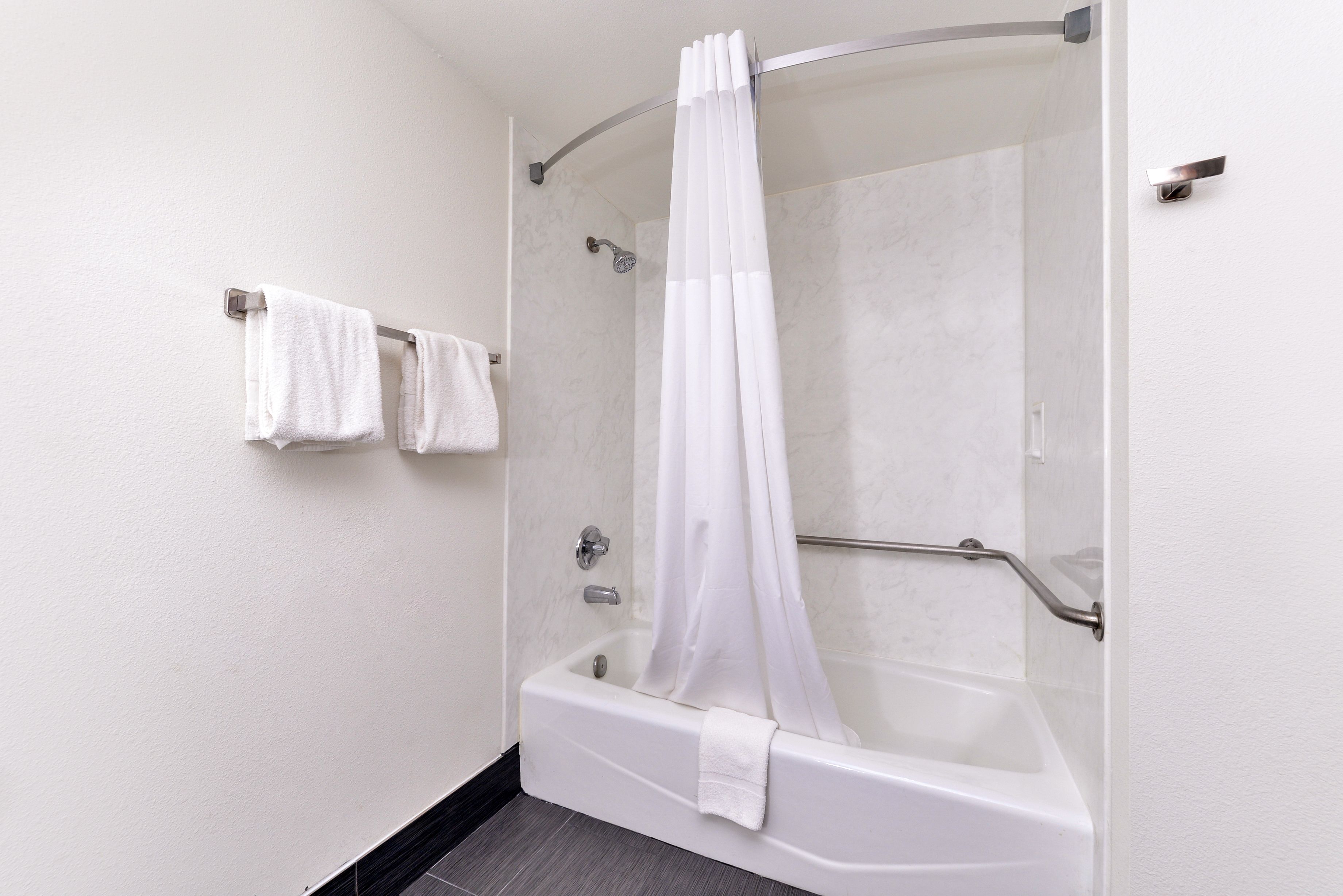 A modern bathroom with a walk-in shower, a bathtub, and a towel rack with two towels.