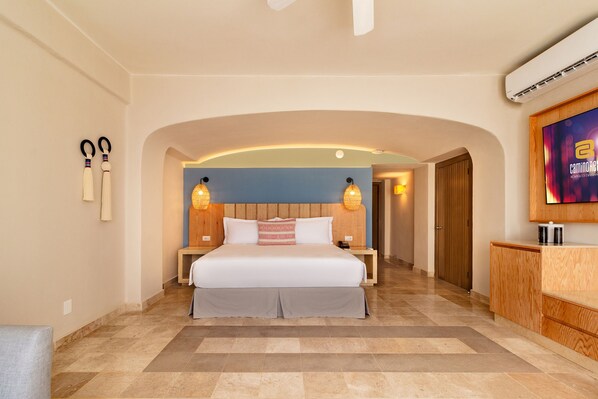Una habitación de hotel con una cama grande, un cabecero de madera, dos lámparas de noche, una mesita de noche, un armario de madera y un televisor en la pared.