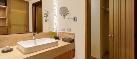 Une salle de bain moderne avec un grand miroir, un lavabo et un espace douche.