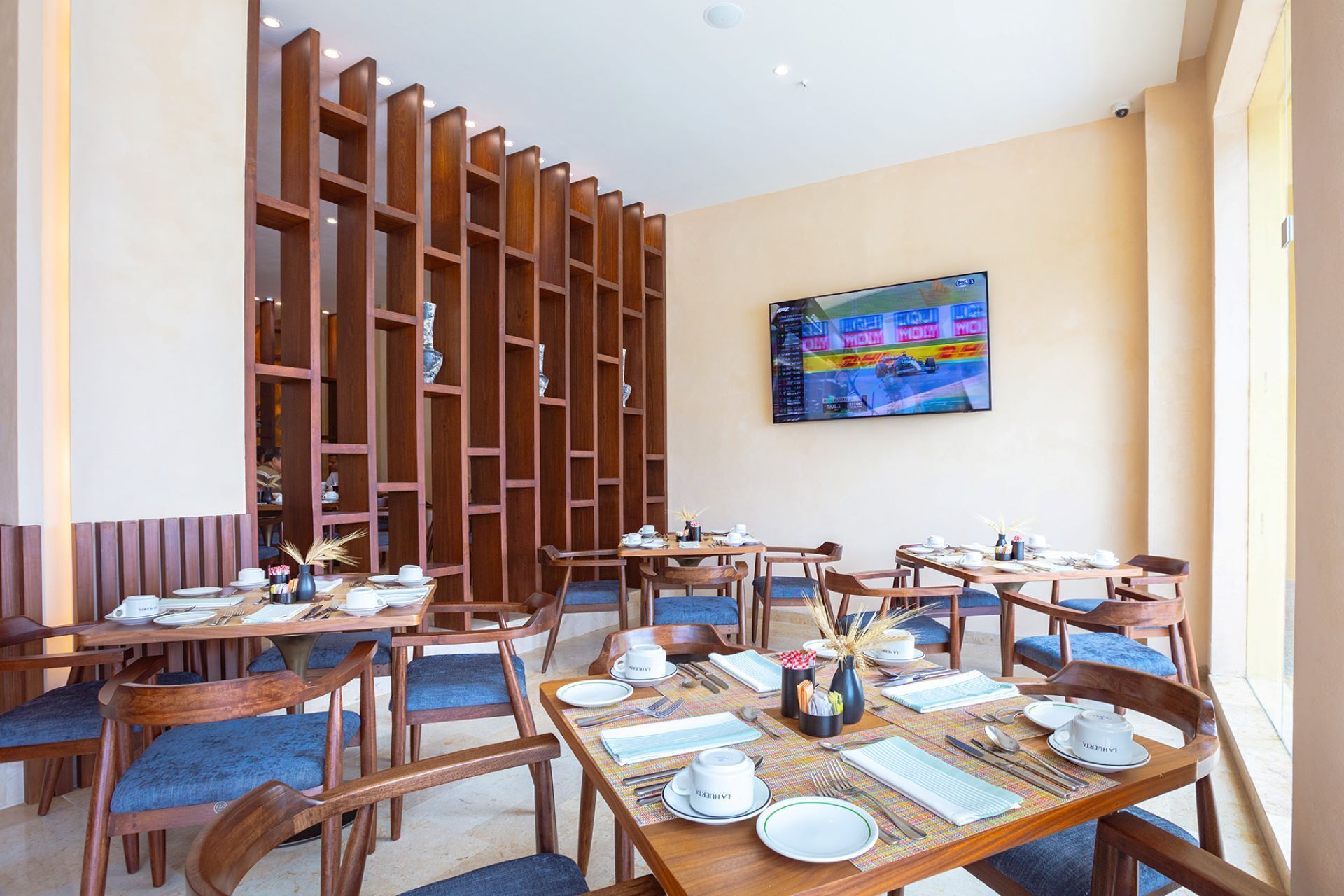A restaurant with wooden furniture, tables set for dining, and a large TV on the wall.