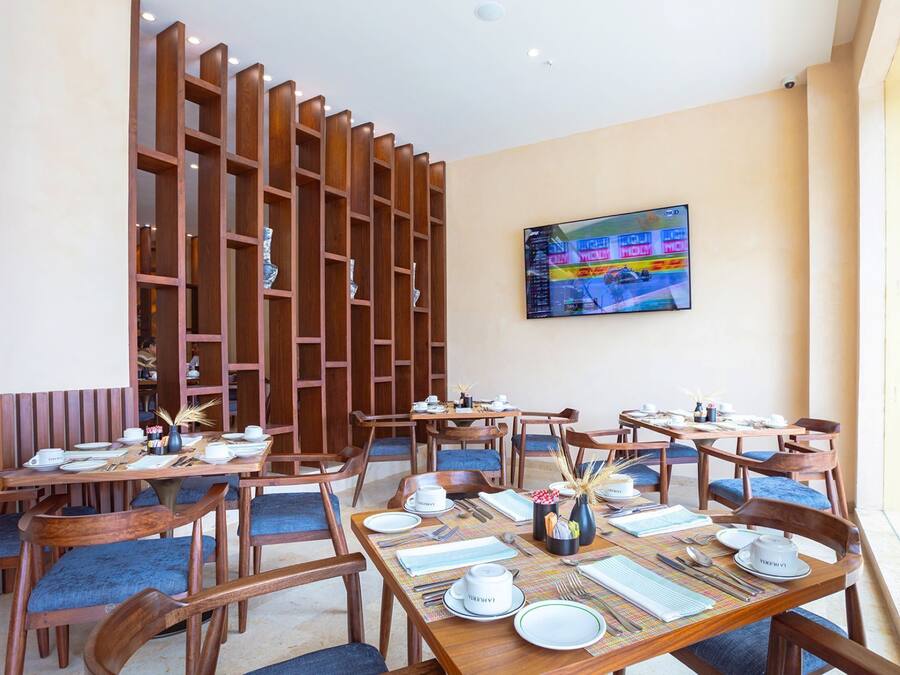 A restaurant with wooden furniture, tables set for dining, and a large TV on the wall.