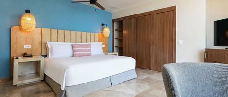Une chambre d’hôtel comprenant un lit, des tables de chevet, un ventilateur de plafond, une armoire et un téléviseur.