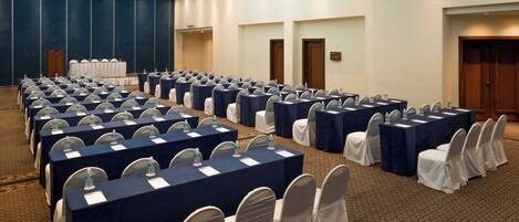 A conference room with rows of tables and chairs, equipped with nameplates and water bottles.