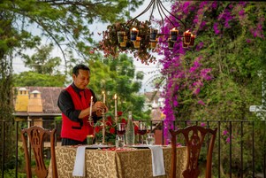Mesa al aire libre decorada con velas, flores y una persona ordenando la mesa.