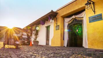 A cobblestone street leading to a building with a sign reading "Hotel Antigua."