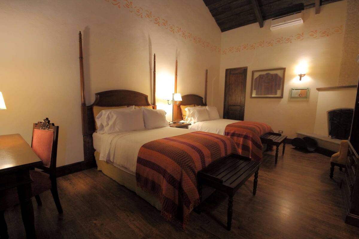 Una habitación de hotel con dos camas, muebles de madera, una mesita y un televisor.