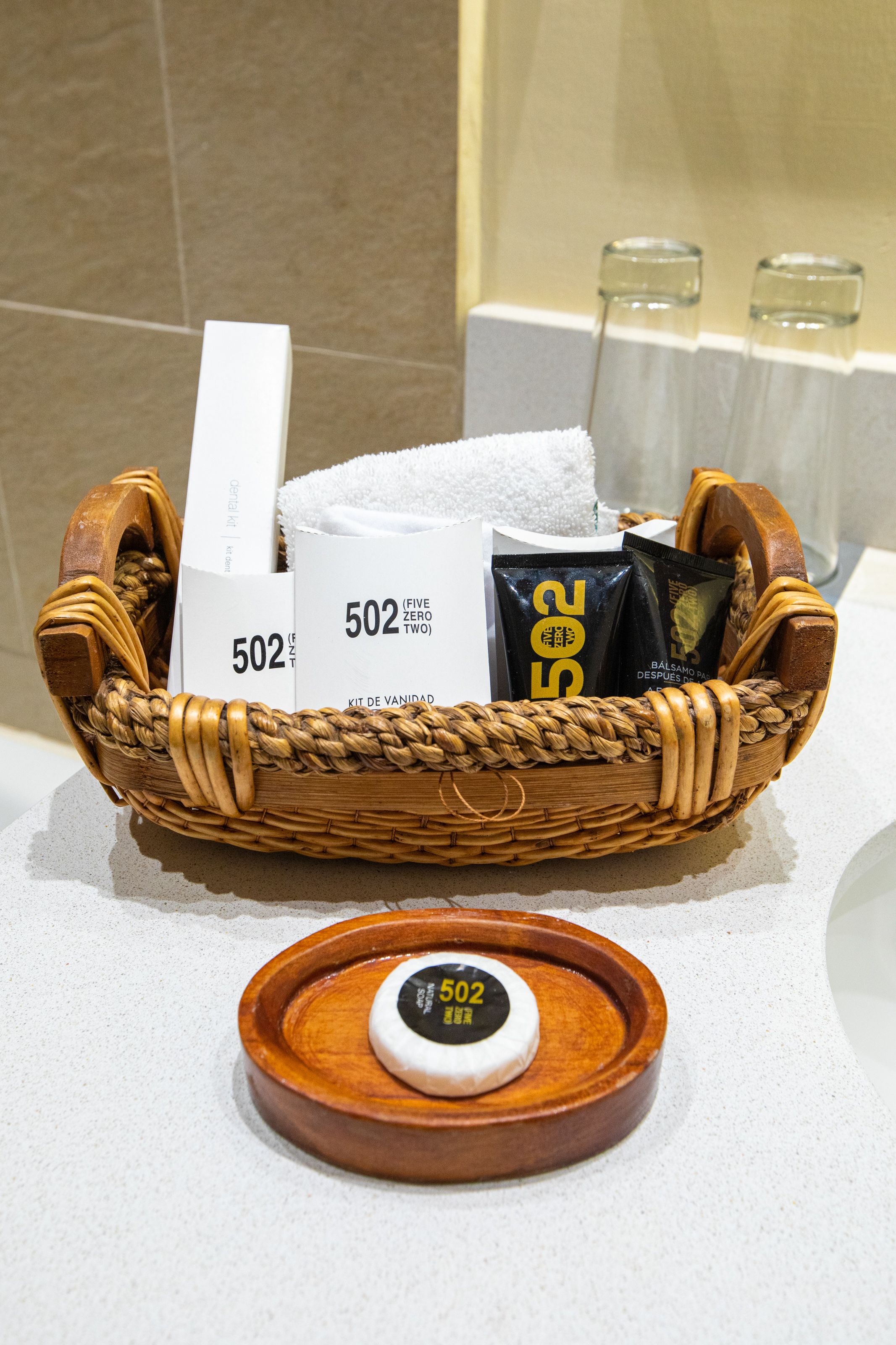 Un panier en osier contenant des articles de toilette et une balance numérique, posés sur le comptoir d’une salle de bain.
