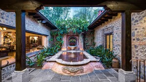 Un patio con una fuente central, paredes de piedra y una zona de estar.