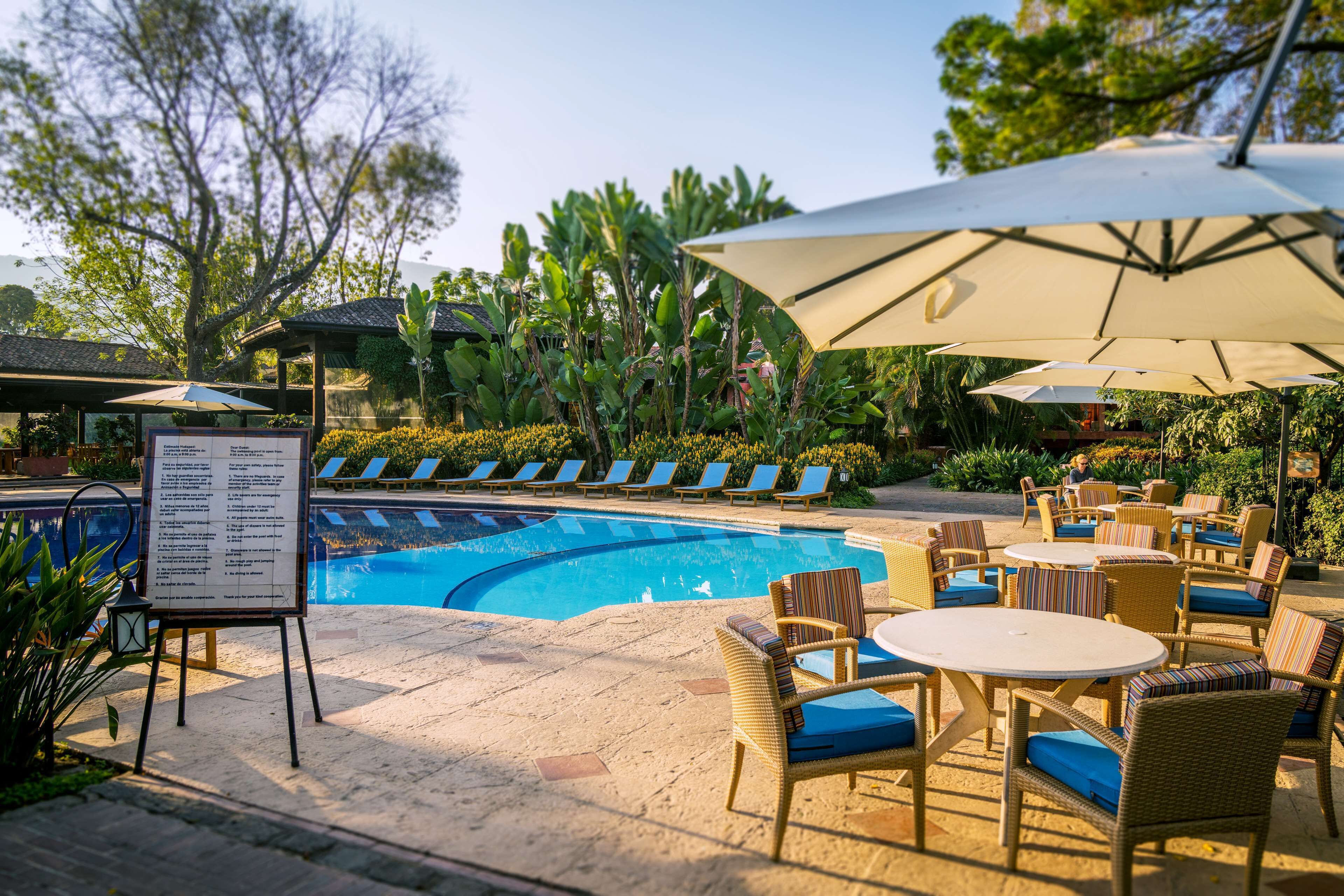 Un espace aménagé au bord de la piscine, avec des chaises longues, des parasols et un panneau affichant le menu.