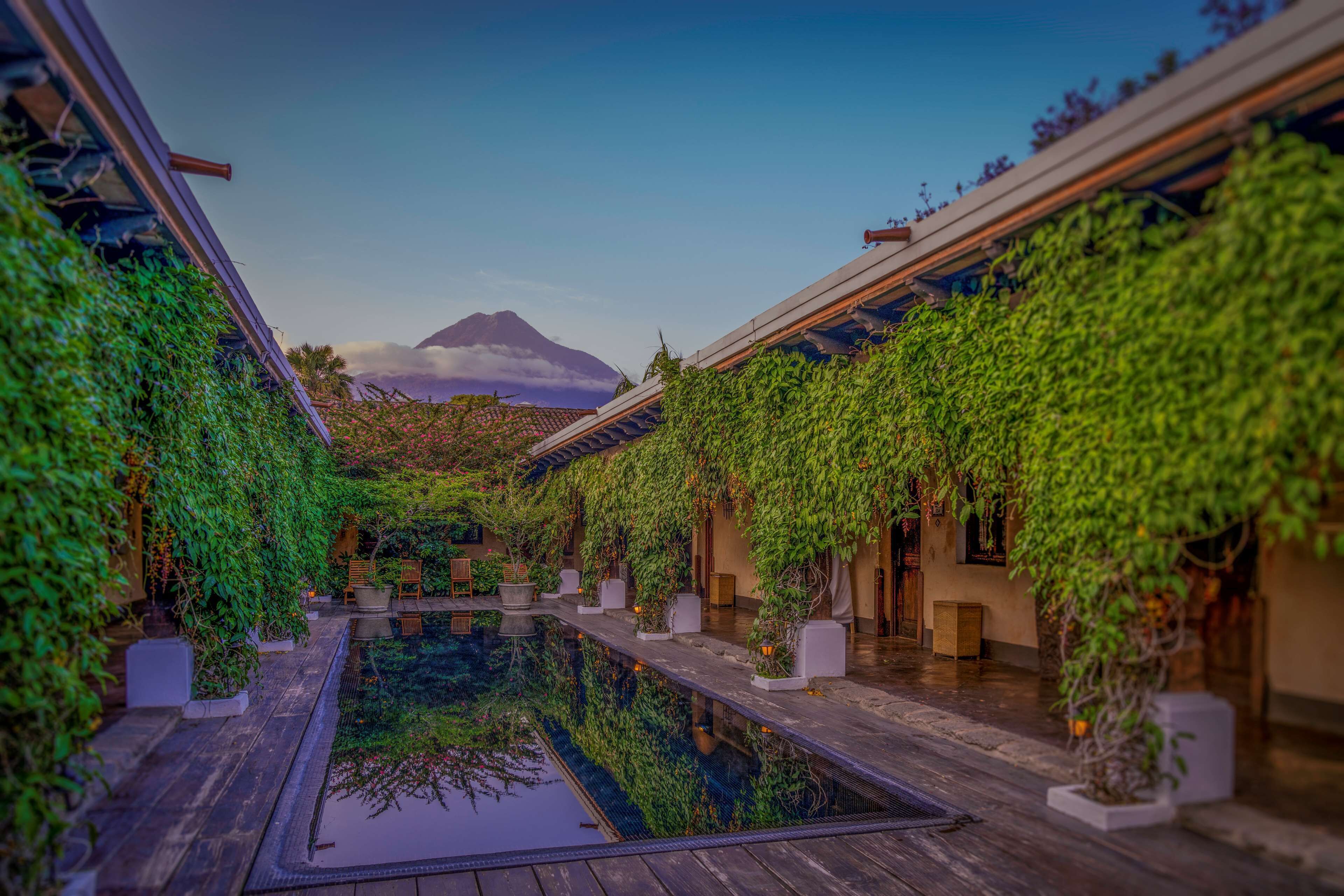 Un patio japonés tradicional con cubierta de madera, plantas en macetas y vistas a la montaña.