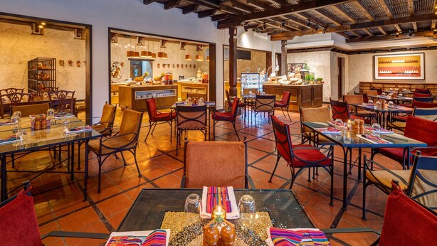 Een restaurant met meerdere tafels en stoelen, een bar en een betegelde vloer.