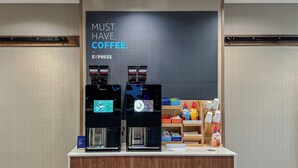 A coffee station with two espresso machines, a sign reading "MUST HAVE COFFEE", and a display of coffee-related products. - Holiday Inn Express Anderson by IHG (Anderson)