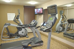 A fitness center with exercise equipment, a treadmill, and a television screen.