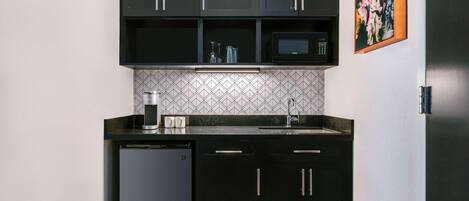 A compact kitchen with dark cabinets, a microwave, a coffee maker, and a dishwasher.