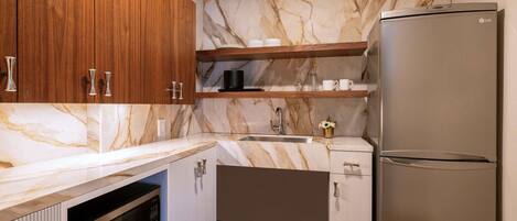 A kitchen with wooden cabinets, a marble backsplash, a stainless steel refrigerator, and a built-in oven.