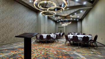 A conference room with multiple tables and chairs, a patterned carpet, and modern chandeliers.