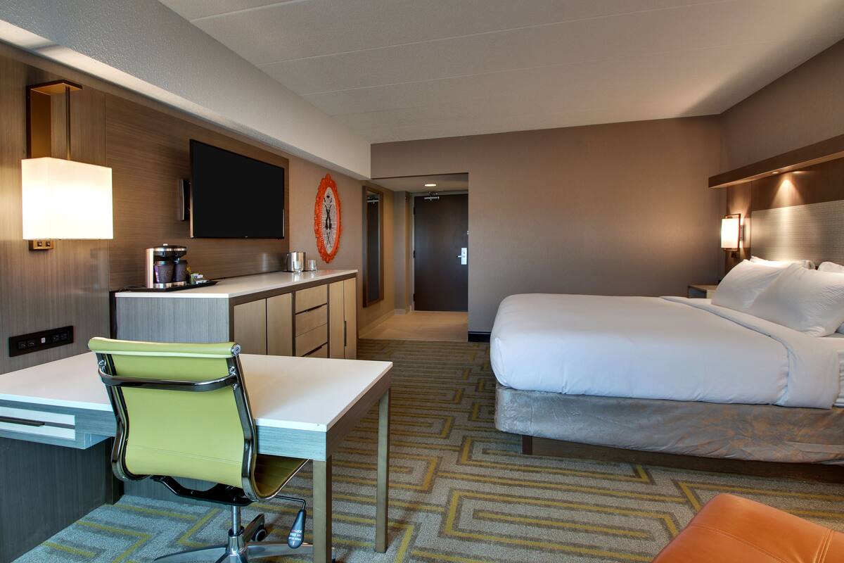 Une chambre d’hôtel équipée d’un lit, d’un bureau avec une chaise, d’une télévision et d’une machine à café.