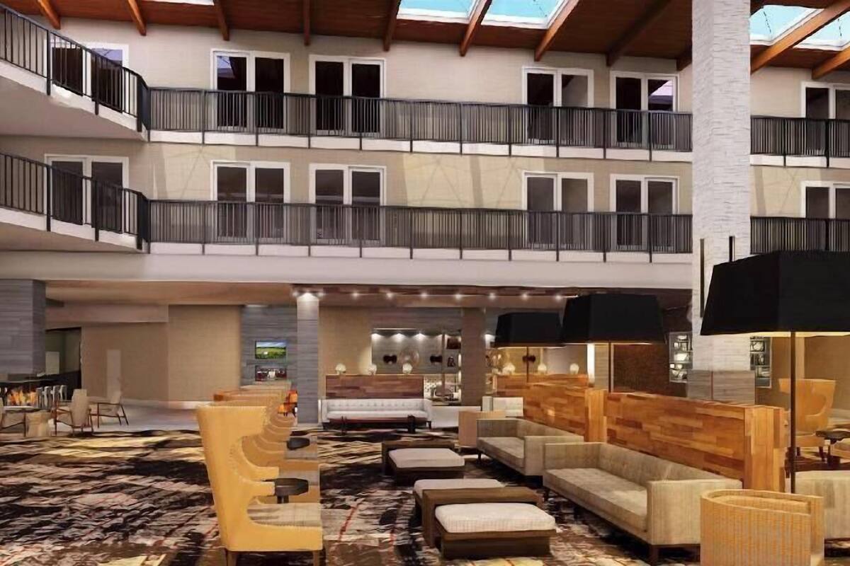 Un hall d’hôtel spacieux, doté d’un plafond haut, de nombreux balcons et d’un espace salon central avec des canapés et des fauteuils.