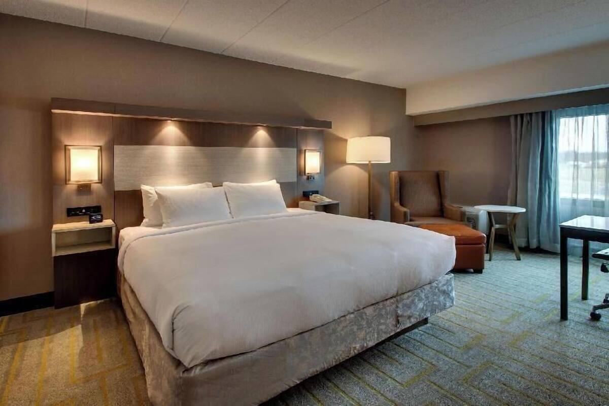 Une chambre d’hôtel avec un grand lit, des lampes de chevet, un bureau et une chaise.