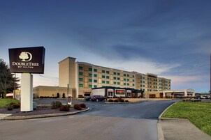 Un hotel DoubleTree by Hilton con un edificio grande, zona de estacionamiento y jardines bien cuidados.