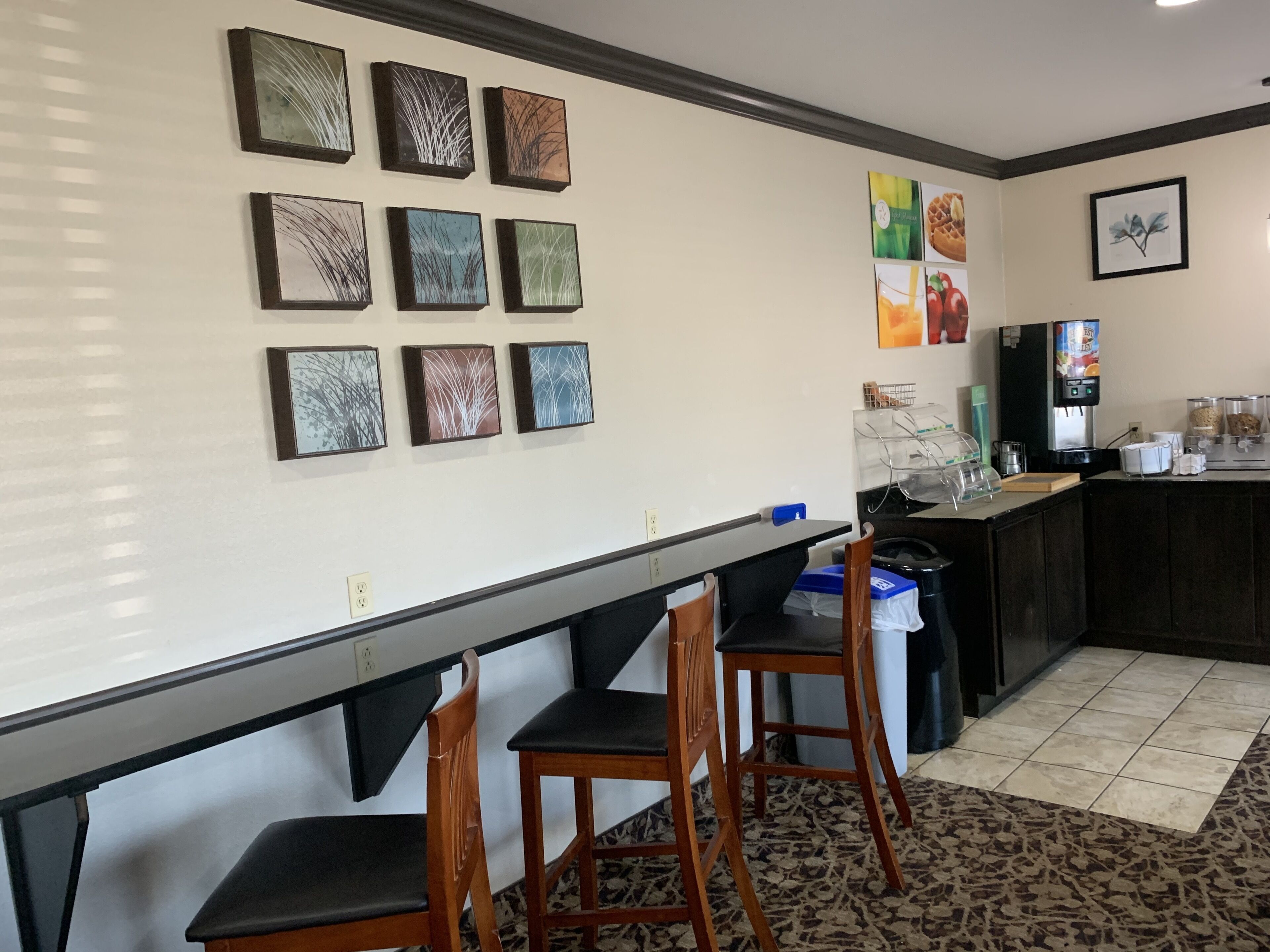 A restaurant with a counter, chairs, and wall art.