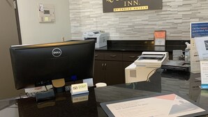 A hotel reception desk with a computer, a sign reading "Quality Inn by Choice Hotels", and a "Stay Here" sign. - Quality Inn Forsyth - Decatur (Forsyth)