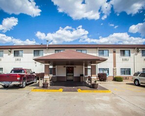 A hotel with a covered entrance, a parking lot, and a red pickup truck parked in front. - Quality Inn Forsyth - Decatur (Forsyth)