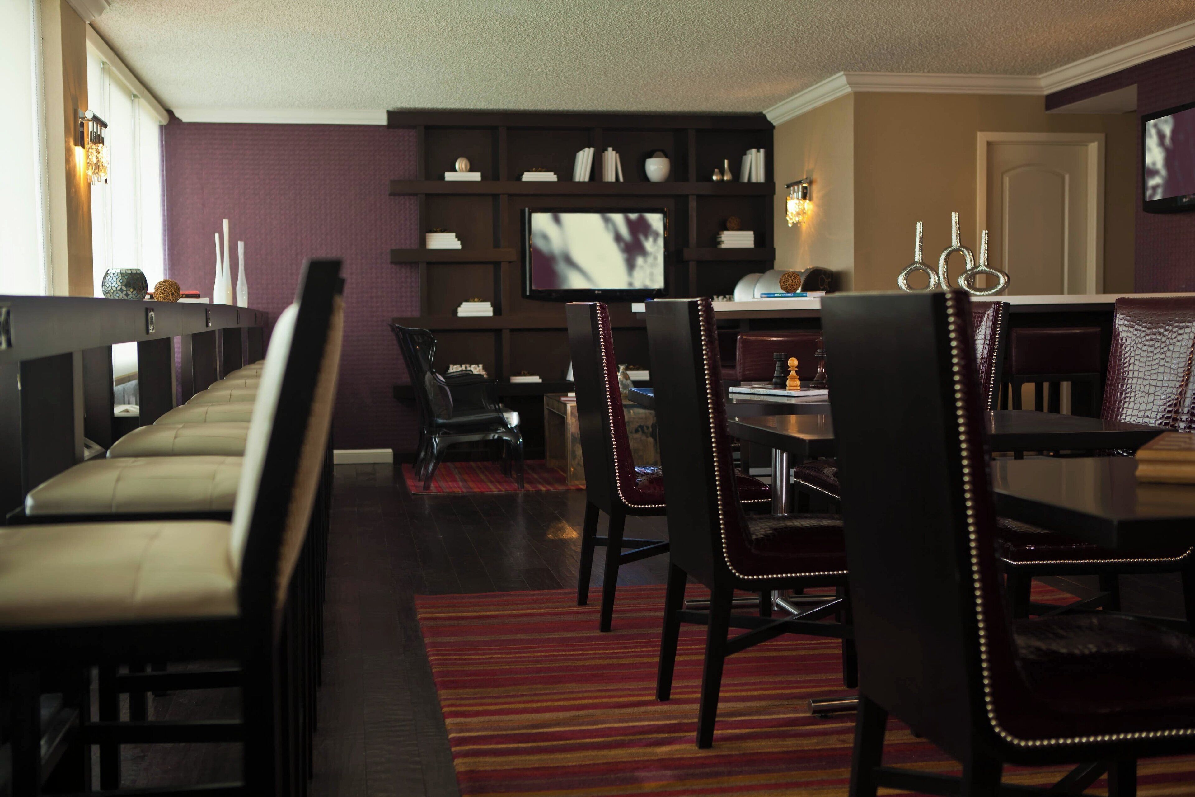 Una sala de estar moderna con un sofá, una mesa de comedor, sillas, un televisor y una estantería.