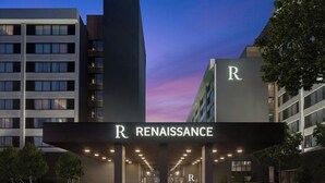 L’entrée d’un hôtel, avec une enseigne bien visible indiquant « Renaissance », une architecture moderne et un ciel dégagé.