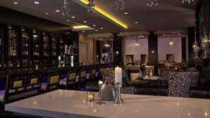 Un espace bar avec une table blanche, des tabourets de bar et une variété de bouteilles et de verres.
